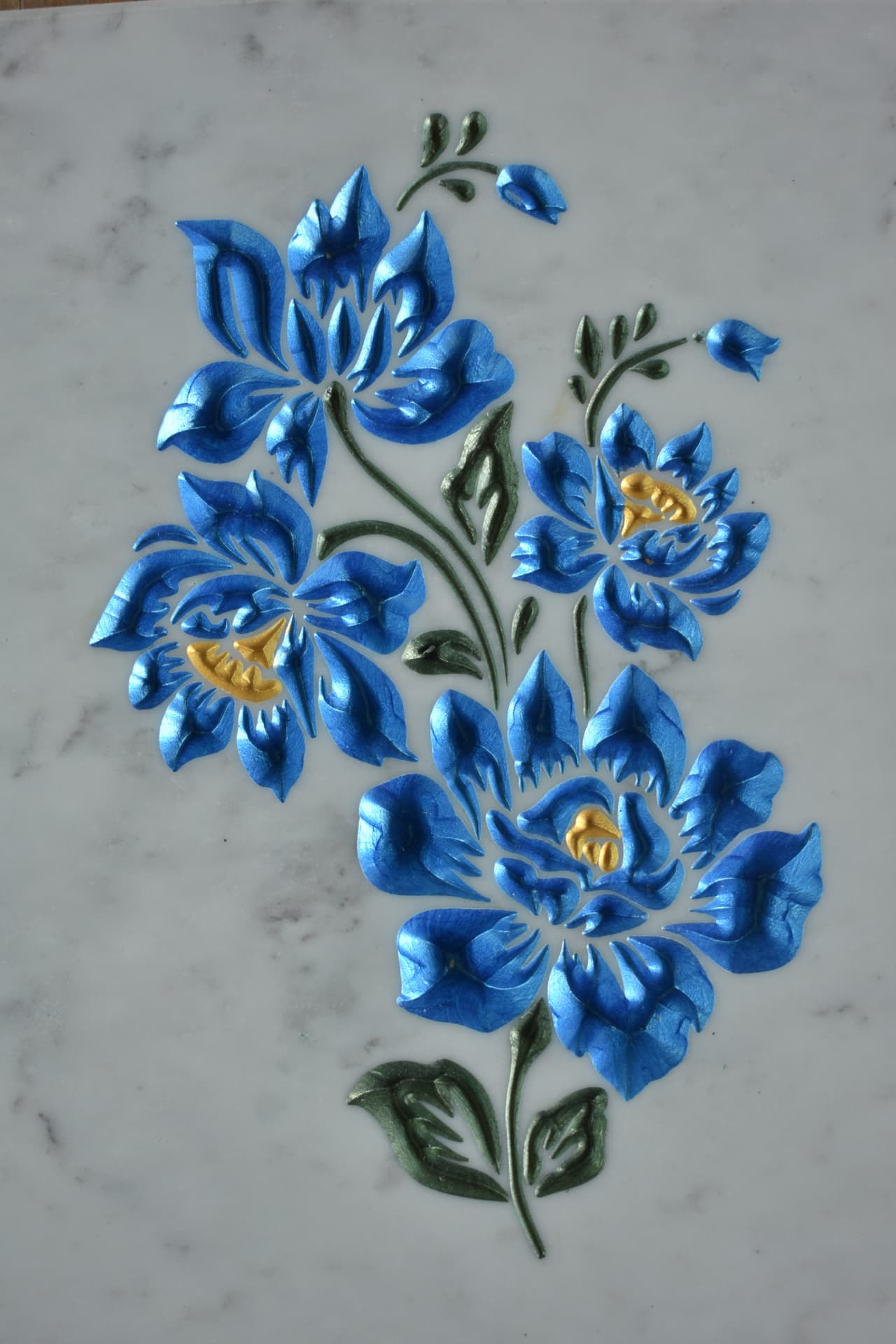 Fiori azzurri e dorati incisi su marmo