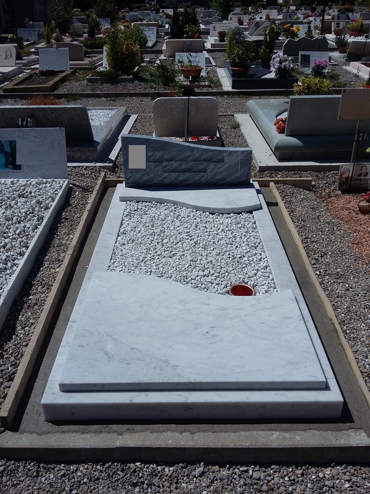 Tomba in marmo bianco di Carrara con stele ondulata in bardiglio e ciottoli bianchi