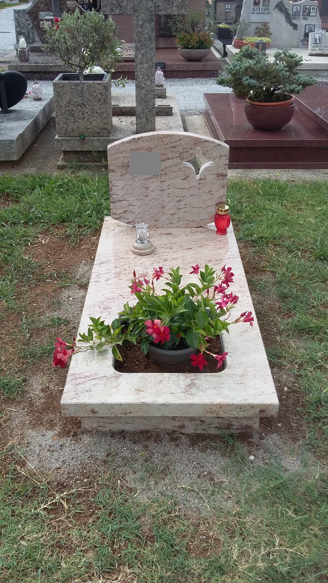 Tomba in granito rosa con stele ad arco, colomba incisa e vasca portafiori