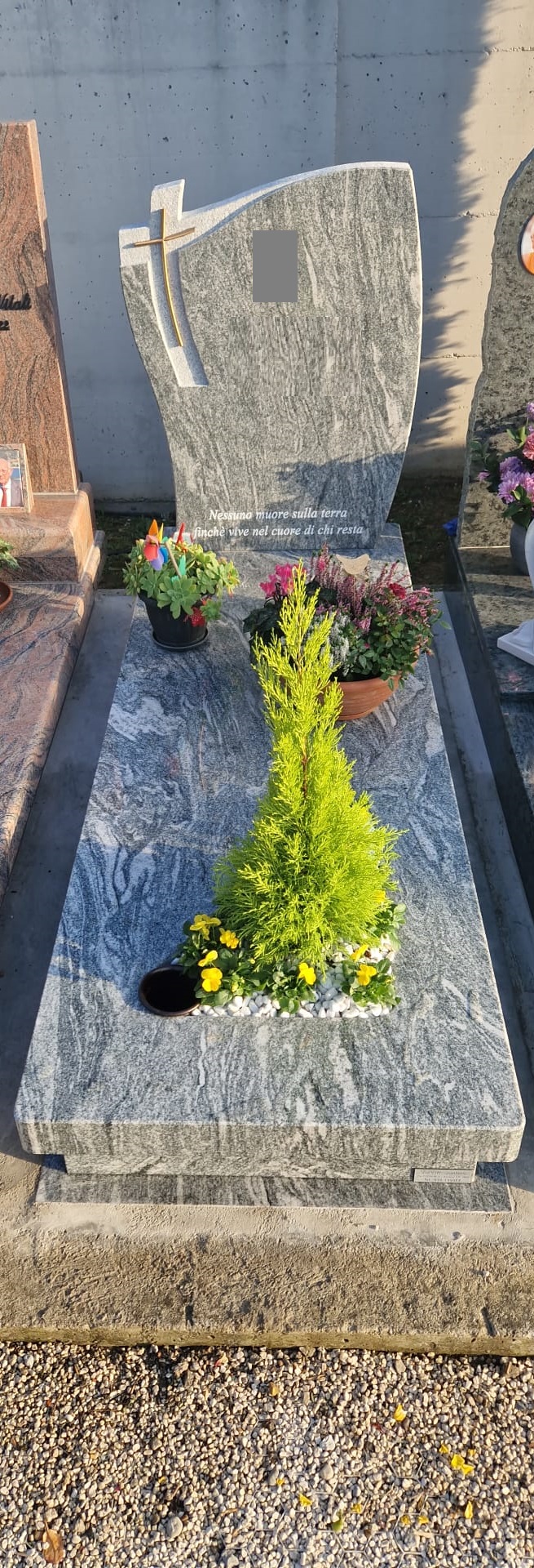 Tomba in granito grigio con croce dorata e incisione dedicatoria