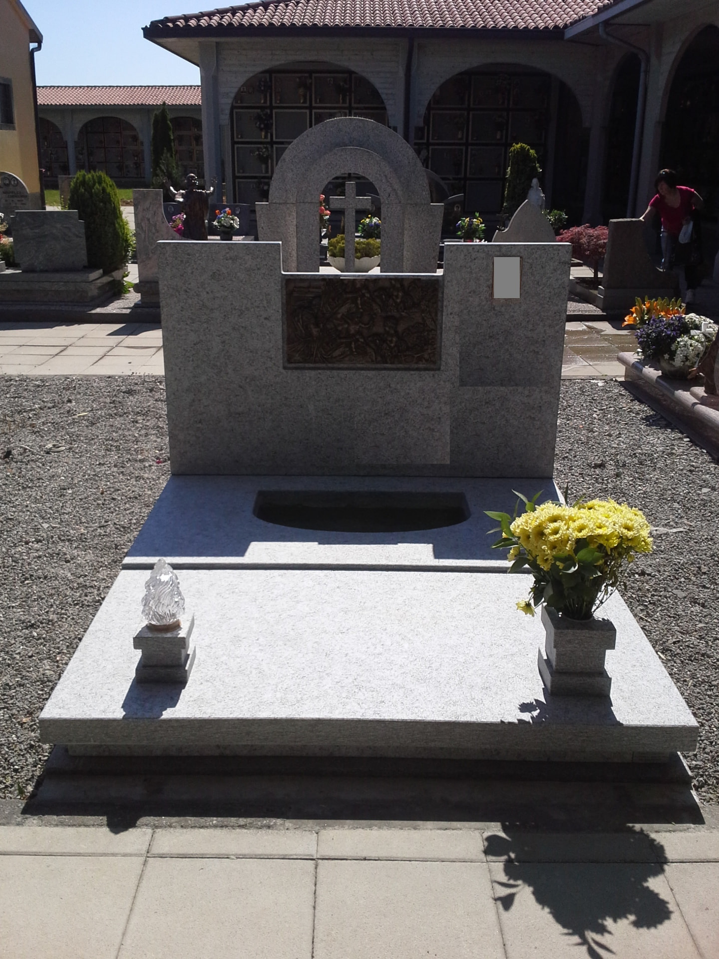 Tomba in granito chiaro con stele ad arco, croce e formella bronzea