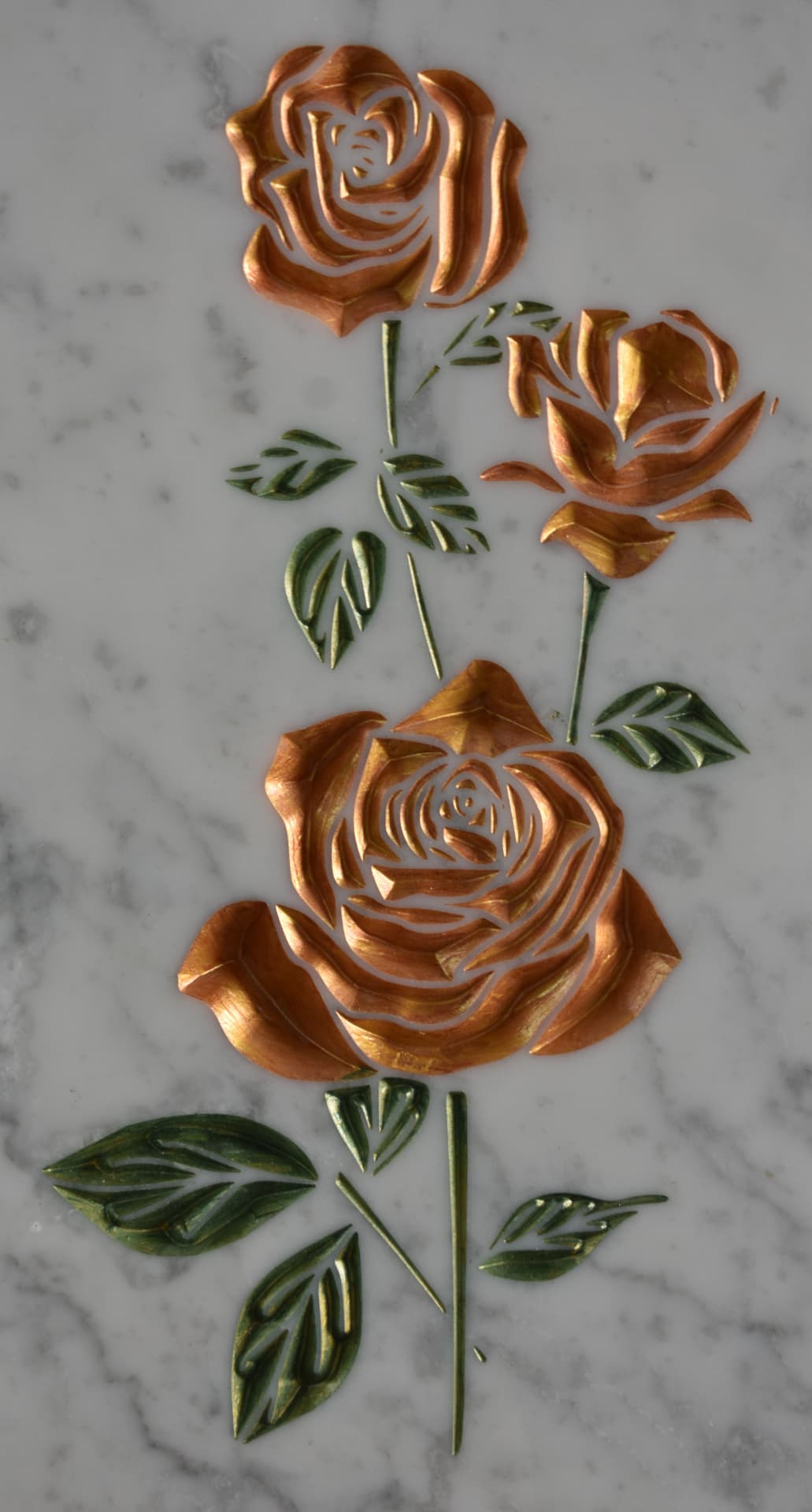 Rose dorate incise su lastra di marmo bianco