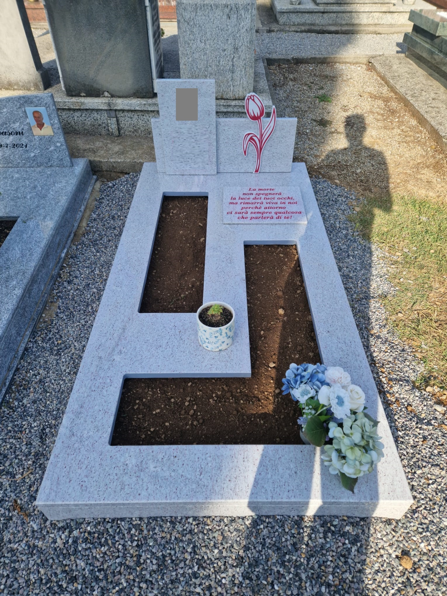 Tomba in granito chiaro con lastra a disegno geometrico e stele doppia con tulipano