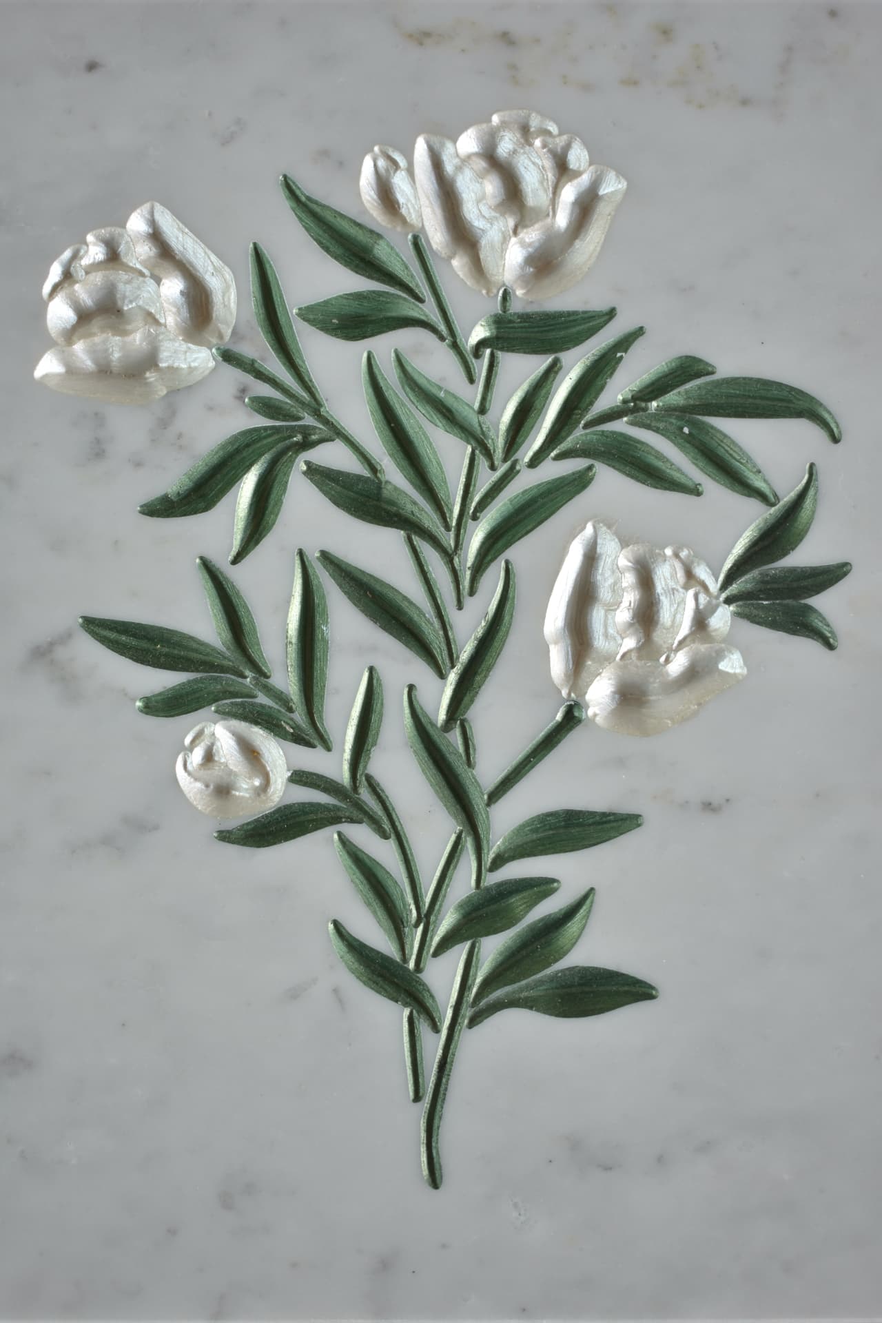Rose bianche e foglie verdi incise su marmo