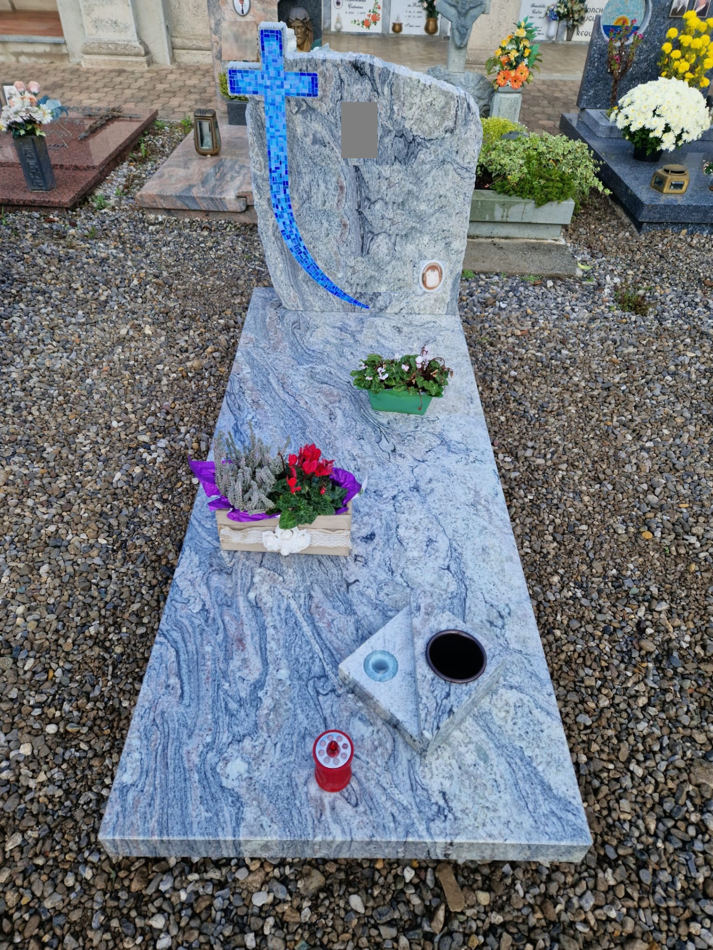 Tomba in granito grigio venato con croce in mosaico azzurro