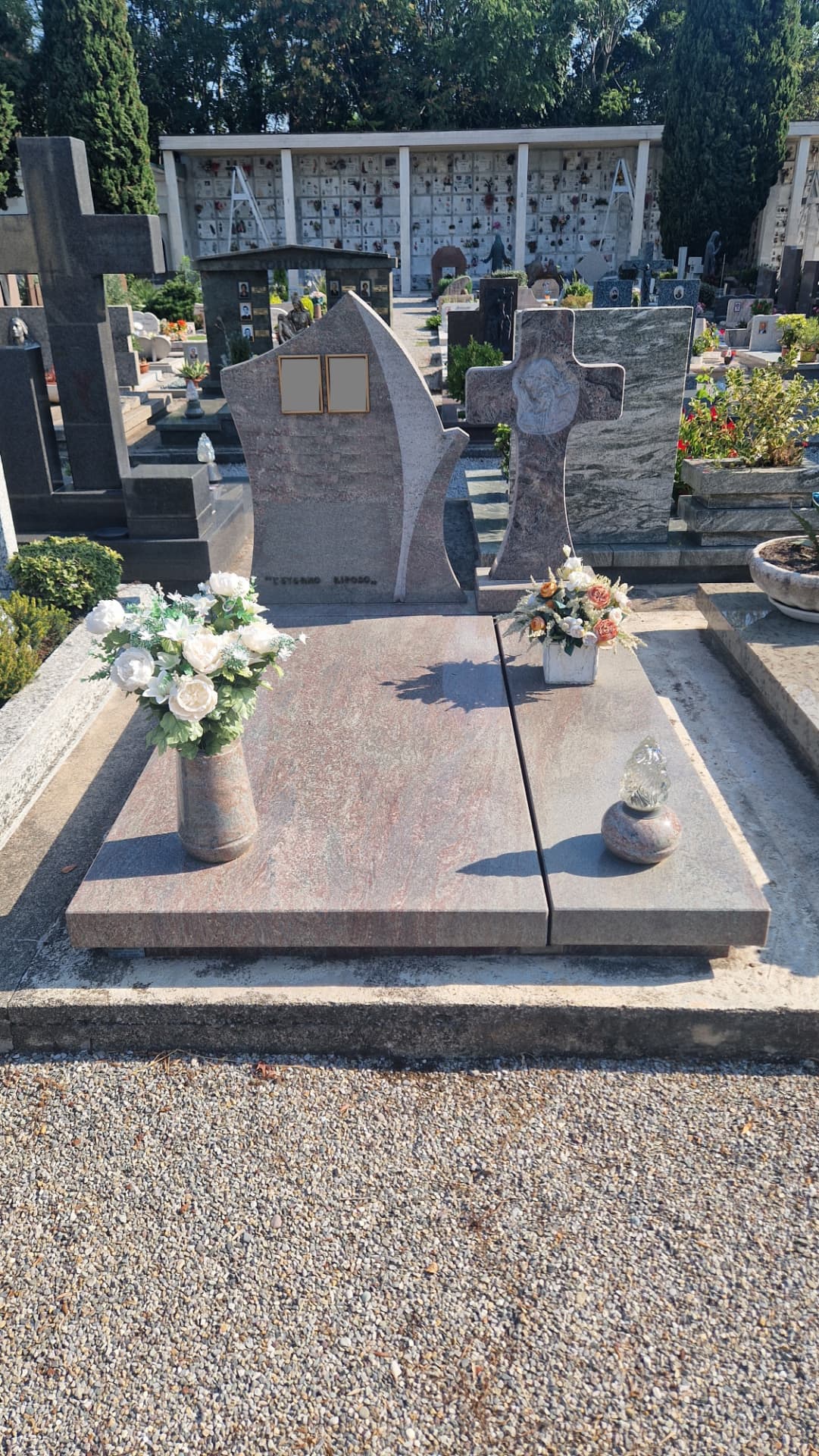 Tomba in granito rosa venato con stele sagomata, croce in pietra e incisione 'L'eterno riposo'