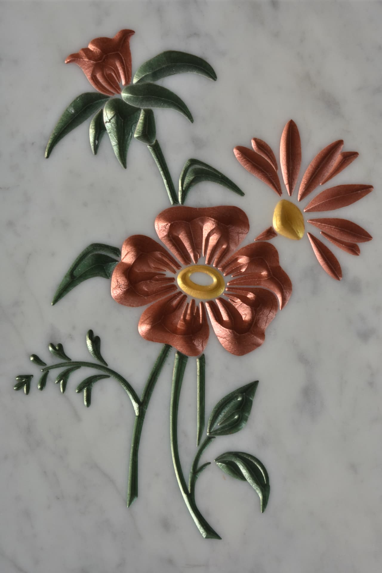 Fiori ramati e margherita incisi su marmo bianco