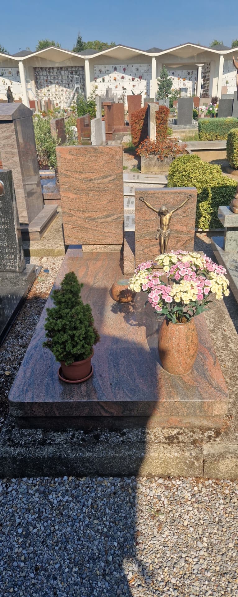 Tomba in granito venato rosso con stele doppia e crocifisso in bronzo