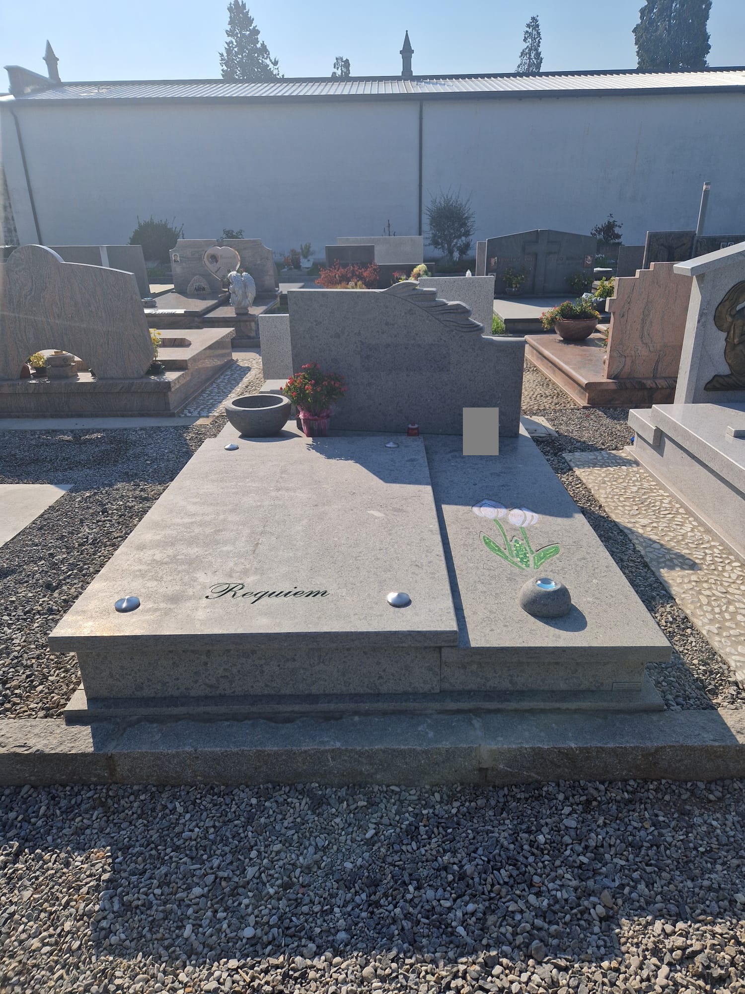 Tomba in granito grigio con stele ondulata, incisione 'Requiem' e mosaico floreale