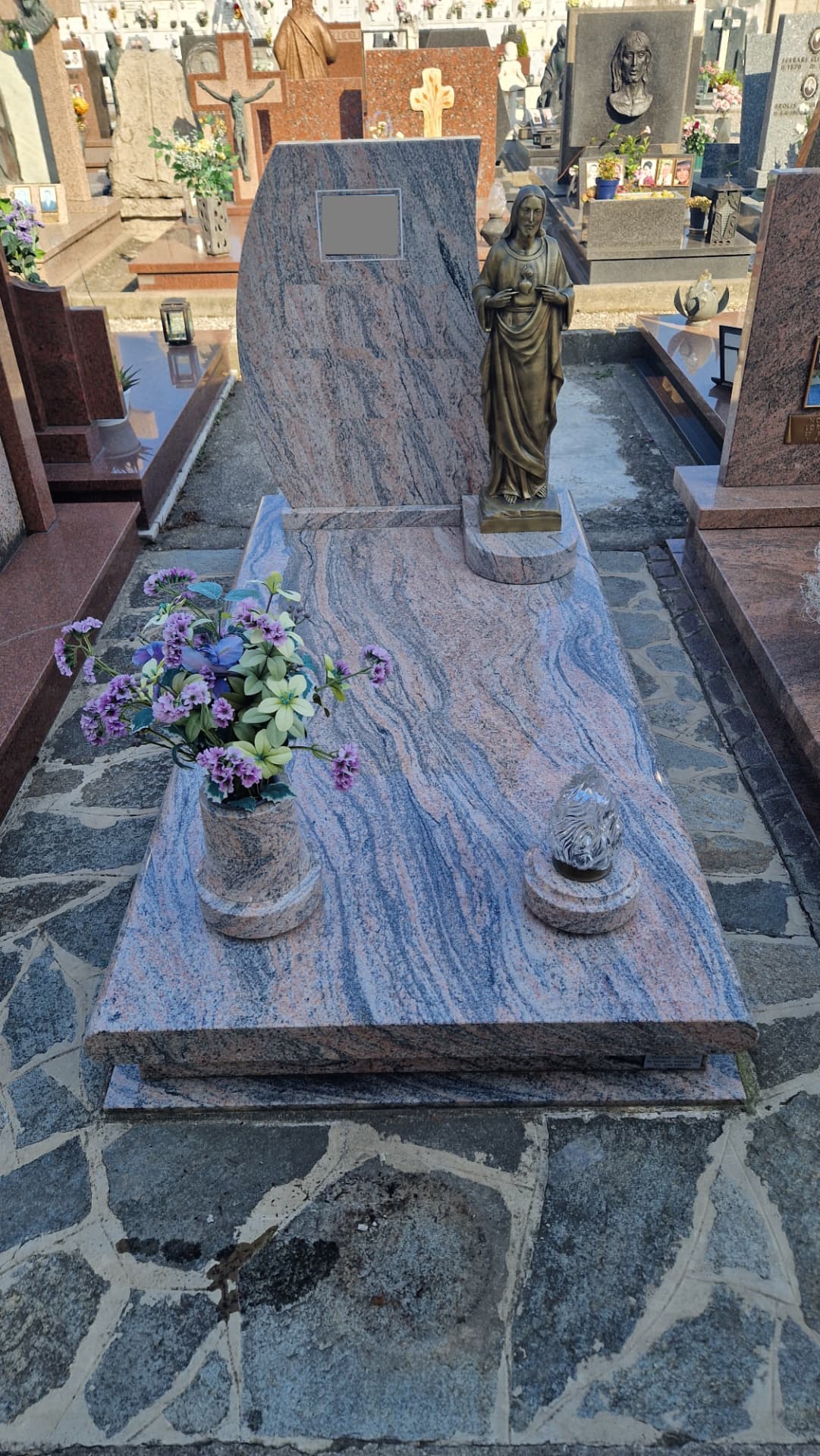 Tomba in granito venato rosa e blu con statua bronzea del Sacro Cuore