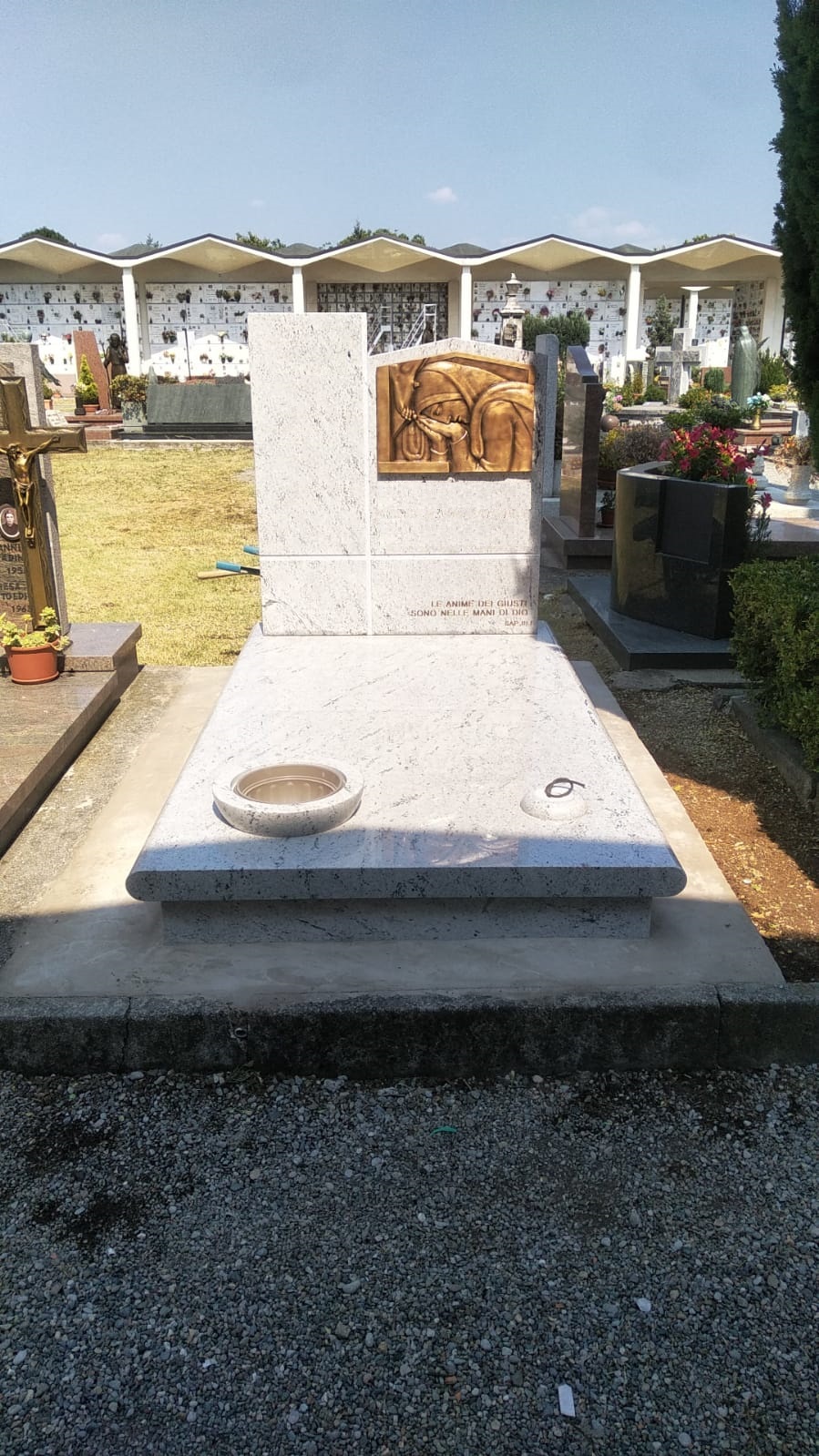 Tomba in granito bianco con formella bronzea e incisione 'Le anime dei giusti sono nelle mani di Dio'