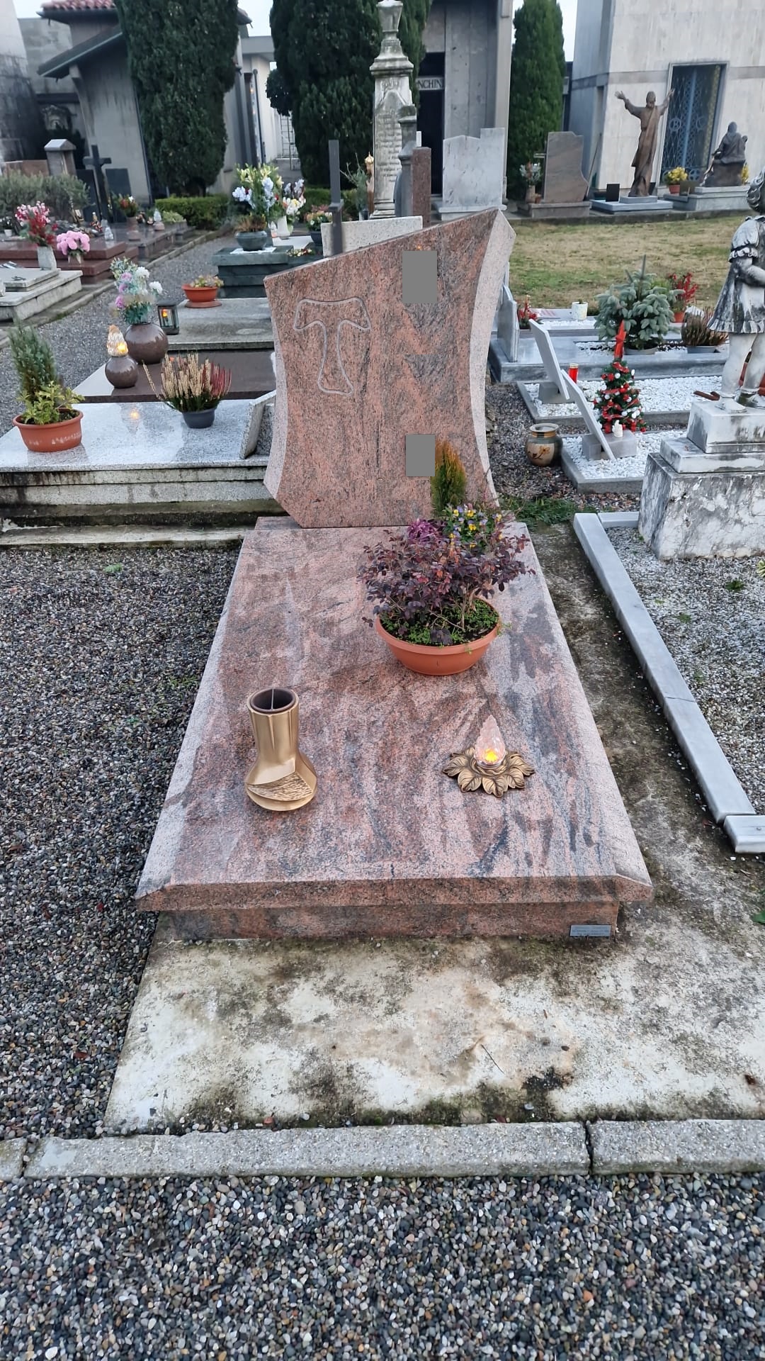 Tomba in granito rosa venato con stele sagomata a vela e incisione del Tau francescano